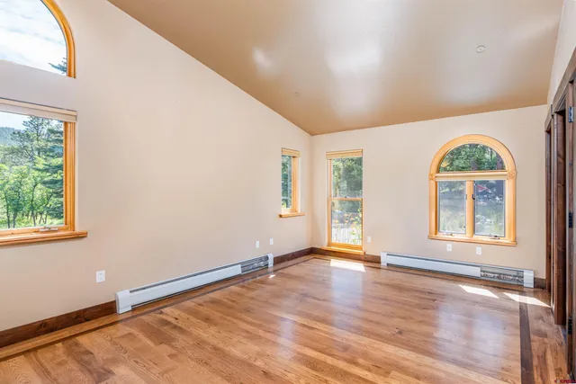 an empty room with wooden floor and windows