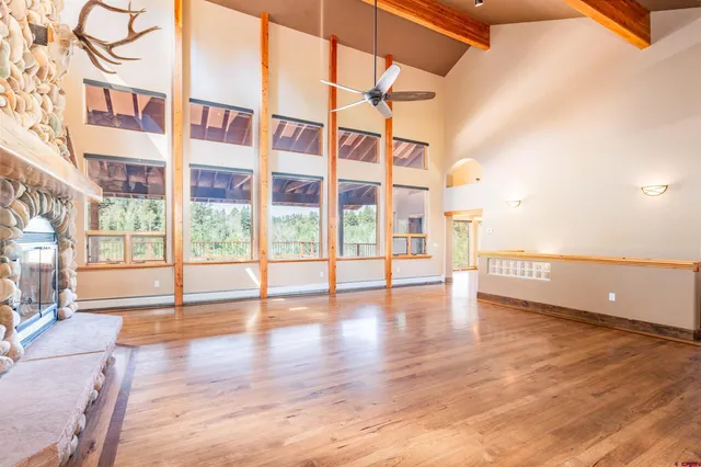 a view of an empty room with wooden floor and windows