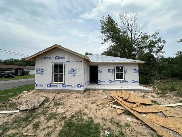 a front view of house with yard and trees in the background