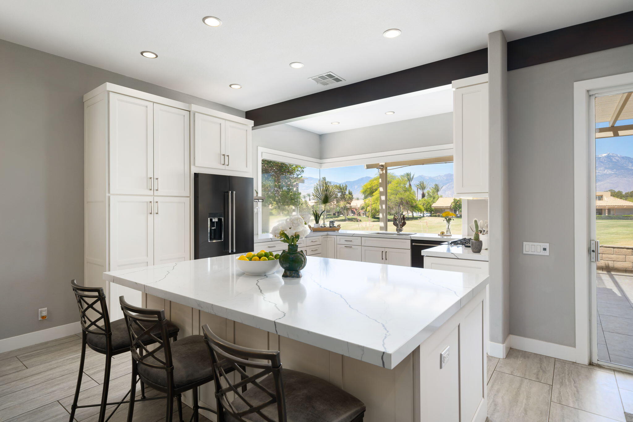 93 Augusta Drive Rancho Mirage, CA 92270 - Photo 16 of 39 a kitchen with stainless steel appliances kitchen island granite countertop a table chairs and a refrigerator