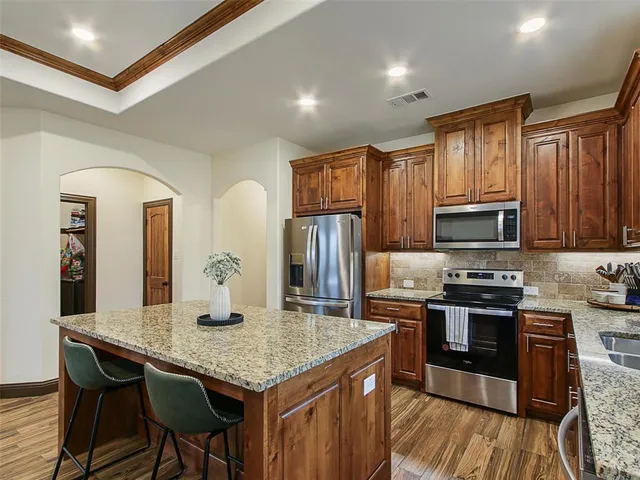 a kitchen with stainless steel appliances granite countertop a stove refrigerator and microwave