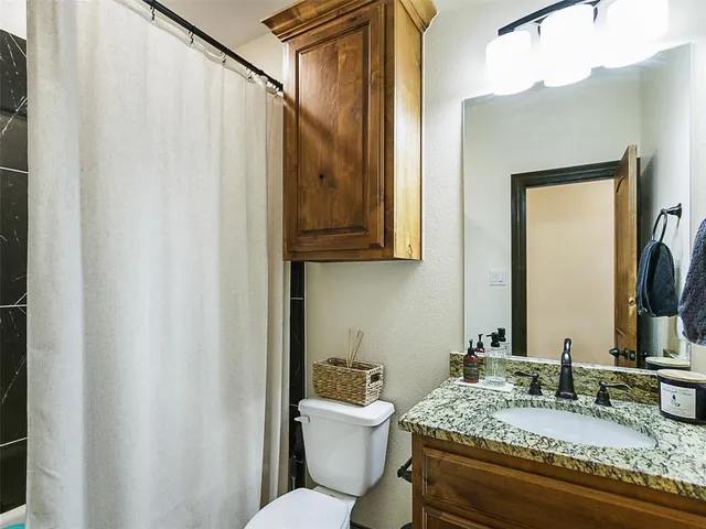 a bathroom with a granite countertop sink mirror vanity and toilet