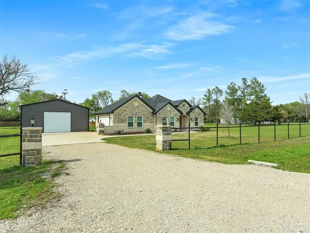 a view of house with a big yard and large trees