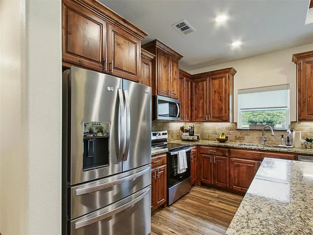 a kitchen with stainless steel appliances granite countertop a refrigerator and a sink