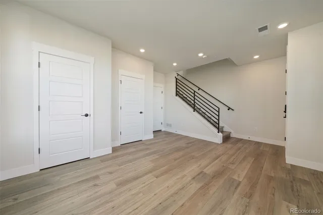 a view of an empty room with wooden floor and stairs