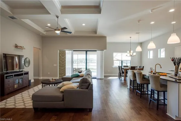 a living room with furniture kitchen view and a wooden floor