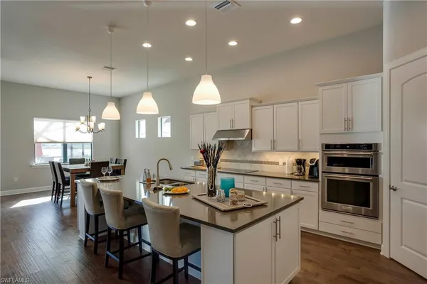 a kitchen with a dining table chairs stove and white cabinets