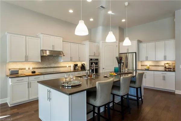 a kitchen with a sink a stove a refrigerator and white cabinets with wooden floor