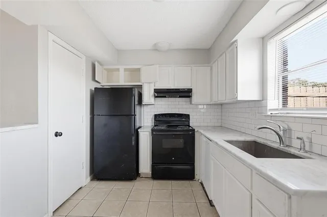a kitchen with a refrigerator sink and cabinets