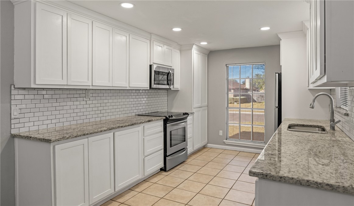 5333 Woodgate Drive Corpus Christi, TX 78413 - Photo 9 of 20 a kitchen with granite countertop white cabinets and stainless steel appliances