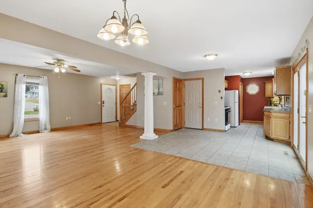 a view of an empty room with wooden floor and a kitchen