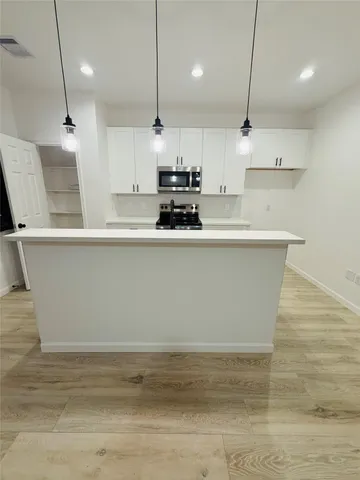 a large kitchen with kitchen island a counter top a stove a sink and a refrigerator