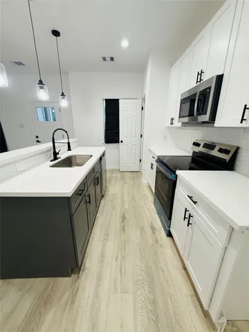 a kitchen with kitchen island a sink a stove oven a counter top space and cabinets