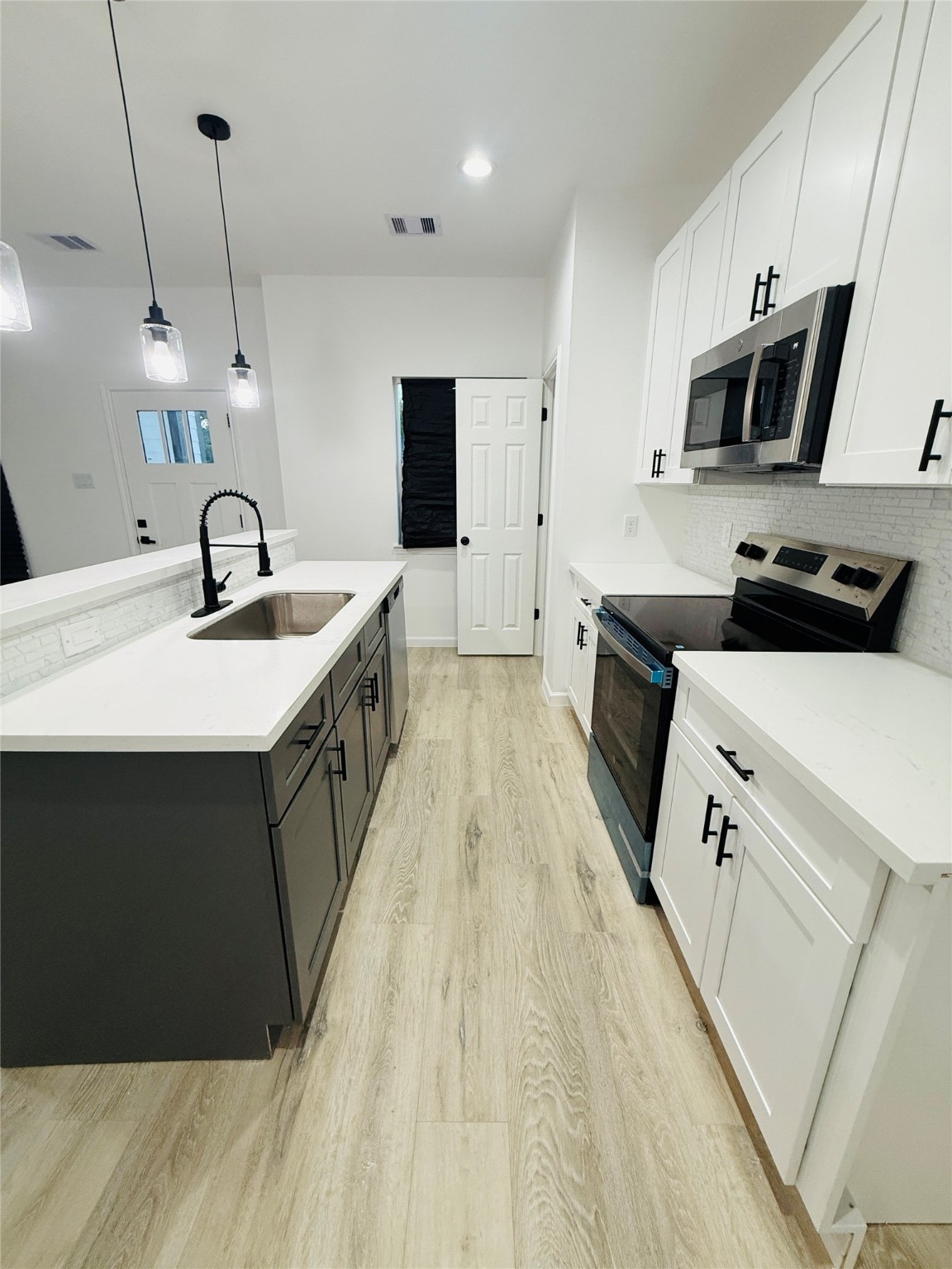 5214 Rue Street, Unit A B Houston, TX 77033 - Photo 10 of 13 a kitchen with kitchen island a sink a stove oven a counter top space and cabinets