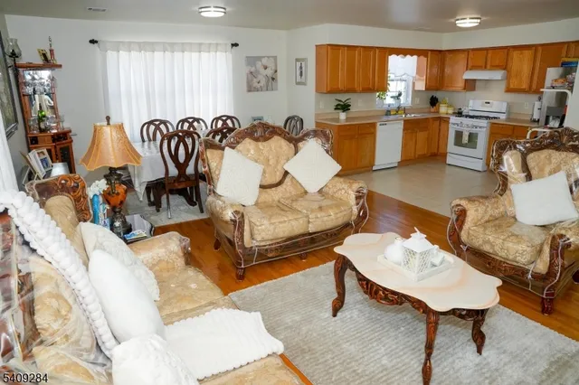 a living room with furniture a rug kitchen view and a large window