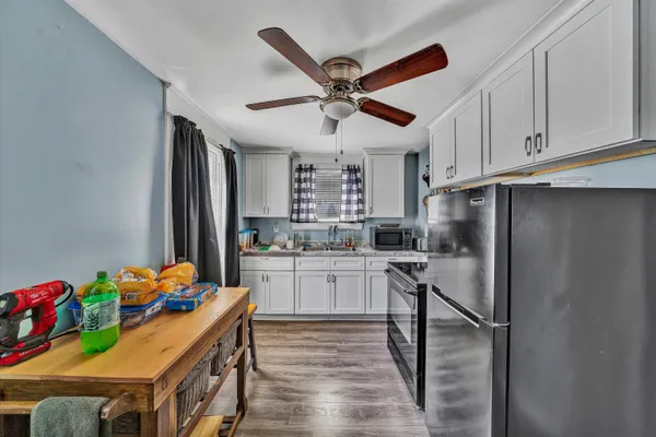 a kitchen with stainless steel appliances granite countertop a refrigerator a sink dishwasher and white cabinets with wooden floor