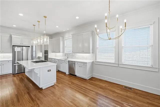 a large kitchen with granite countertop a large counter top a sink stainless steel appliances and cabinets