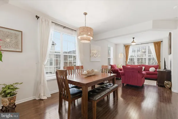 a dining room with wooden floor a chandelier a wooden table and chairs