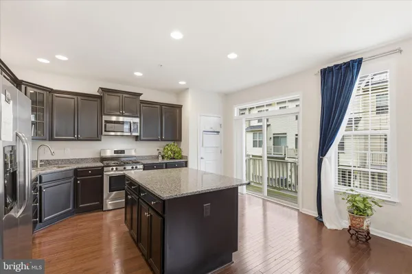 a large kitchen with stainless steel appliances granite countertop a sink stove and refrigerator