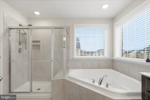a bathroom with a bathtub a shower and a window