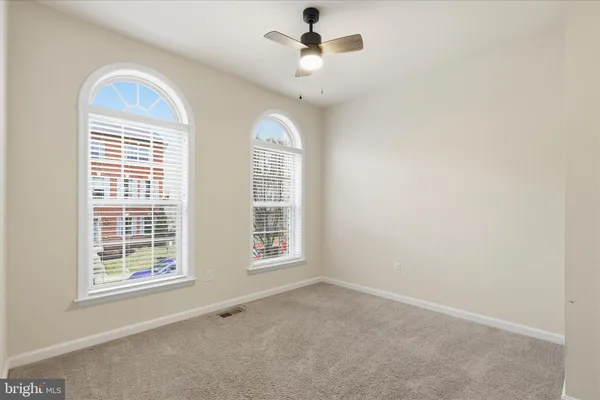 an empty room with windows and chandelier fan