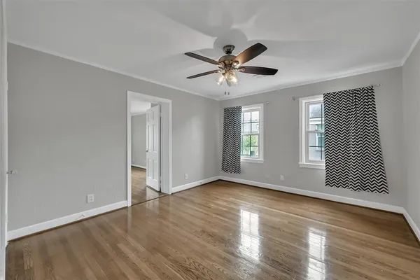 a view of an empty room with wooden floor and a window