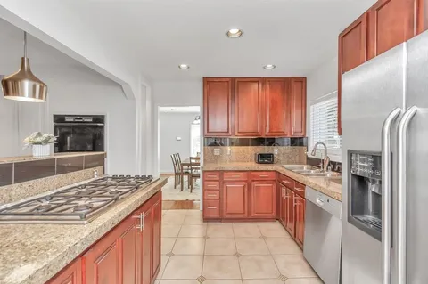 a kitchen with stainless steel appliances granite countertop a stove top oven a sink dishwasher and a refrigerator