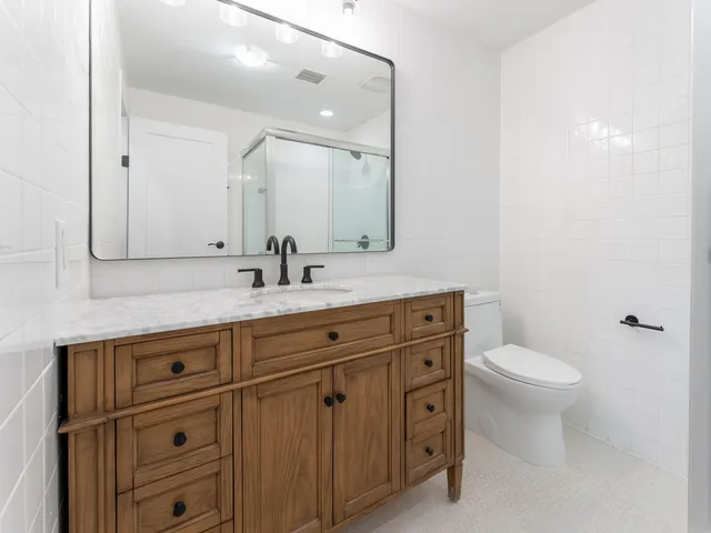 a bathroom with a double vanity sink toilet and a mirror
