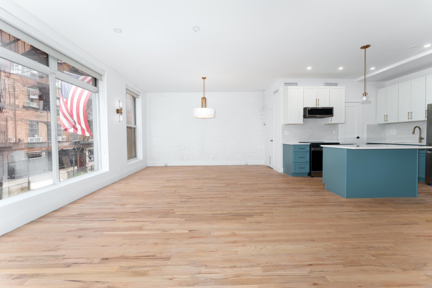 121 Division Street, Unit 2A Manhattan, NY 10002 - Photo 2 of 23 a large white kitchen with kitchen island a stove a sink dishwasher and a oven with wooden floor