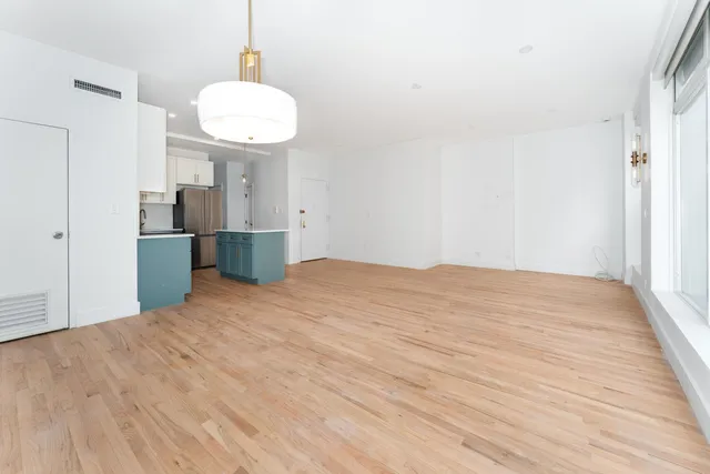 a large white kitchen with kitchen island a stove a sink dishwasher and a oven with wooden floor