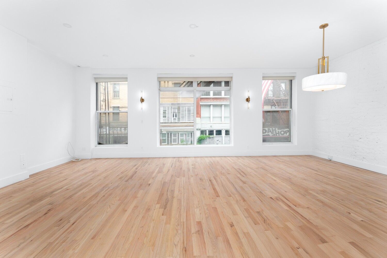 121 Division Street, Unit 2A Manhattan, NY 10002 - Photo 4 of 23 a view of an empty room with wooden floor and a window