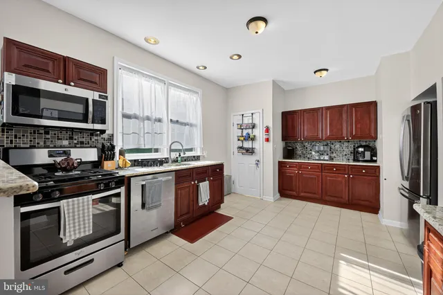 a kitchen with stainless steel appliances granite countertop a stove top oven a sink dishwasher a refrigerator and cabinets with wooden floor