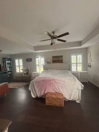 a spacious bedroom with a bed painting on wall and windows