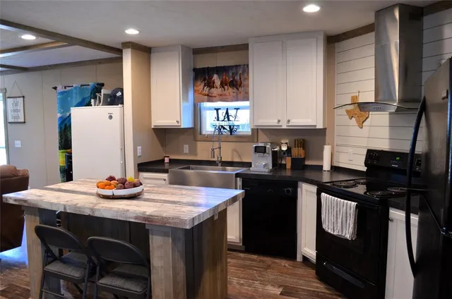 a kitchen with granite countertop kitchen island wooden cabinets a refrigerator a sink a stove and a refrigerator