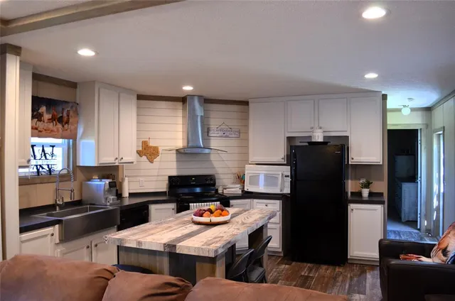 a kitchen with stainless steel appliances kitchen island granite countertop a refrigerator a stove a sink a dining table and chairs