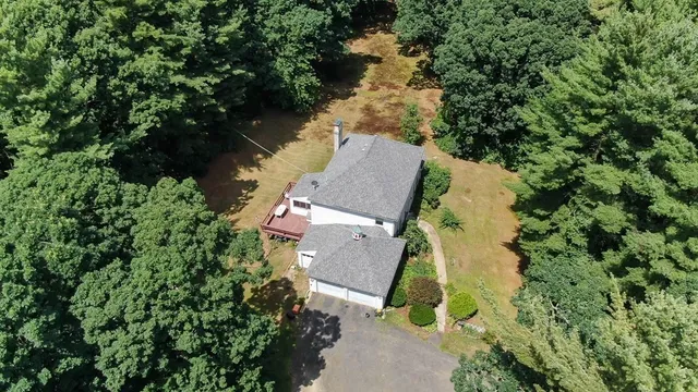 an aerial view of residential house with outdoor space and trees all around