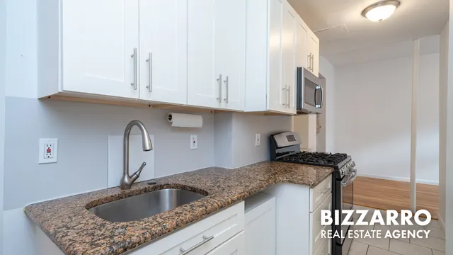 a kitchen with granite countertop a sink a stove and cabinets