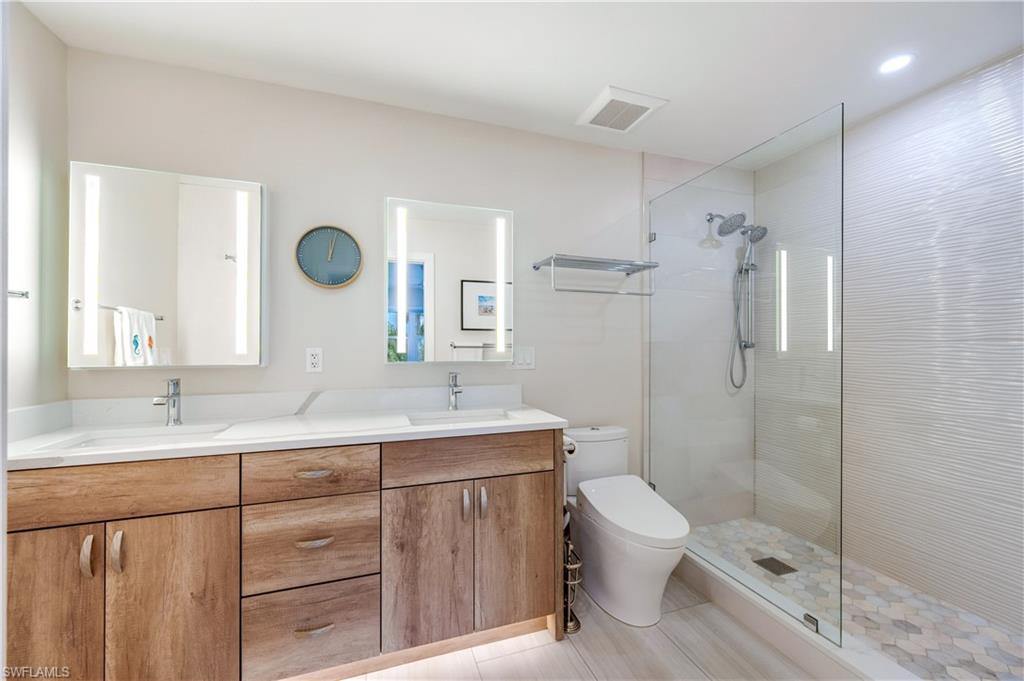 1021 3rd Street South, Unit 310 Naples, FL 34102 - Photo 11 of 20 a bathroom with a double vanity sink toilet mirror and shower