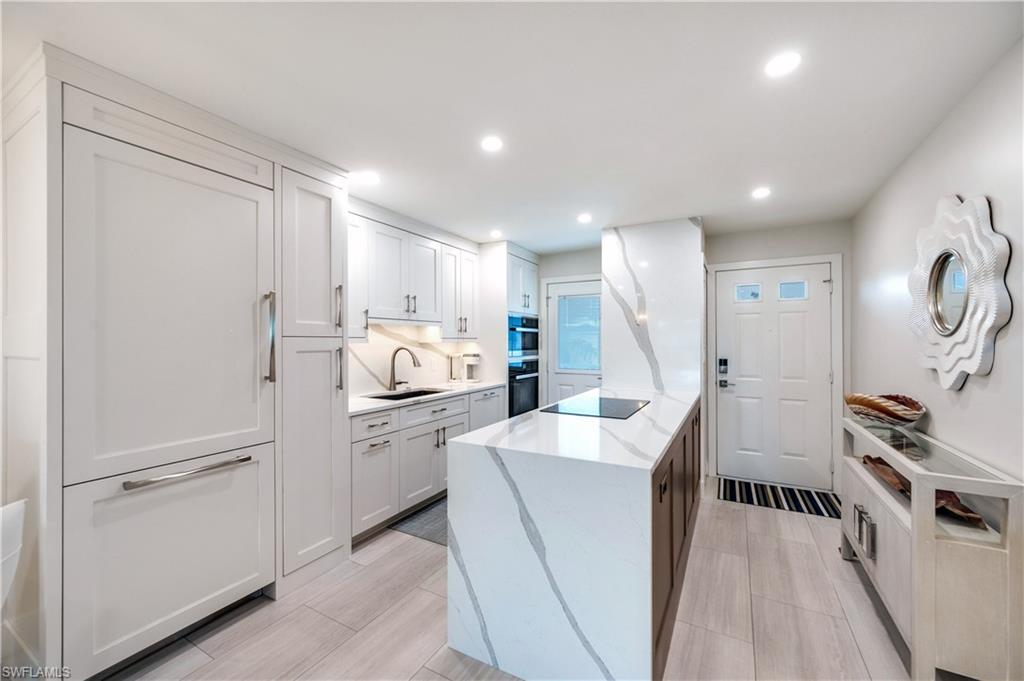 1021 3rd Street South, Unit 310 Naples, FL 34102 - Photo 2 of 20 a kitchen with white cabinets and stainless steel appliances