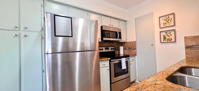 a kitchen with stainless steel appliances granite countertop a refrigerator a stove and a sink with wooden floor