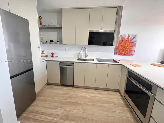 a kitchen with stainless steel appliances a sink a stove a microwave and refrigerator