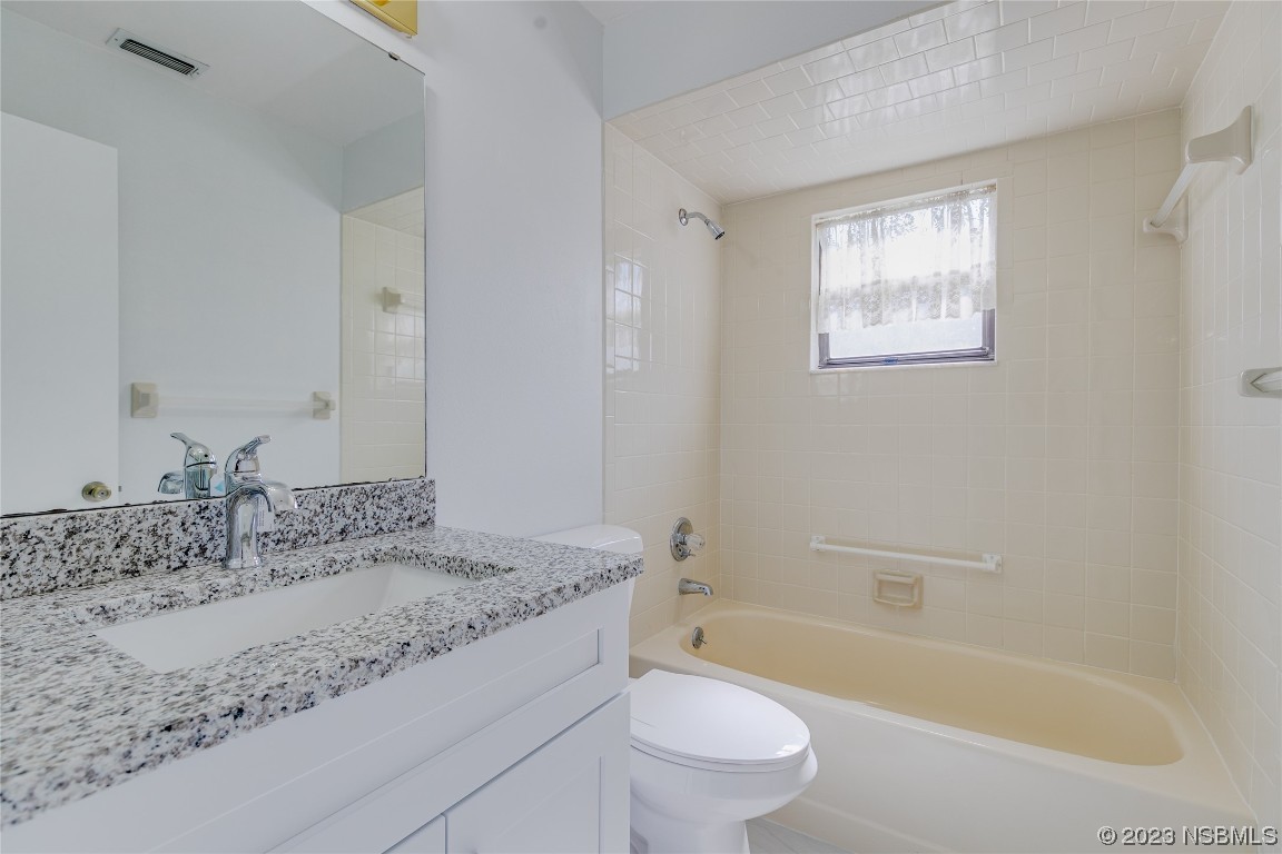 404 Sea Gull Court Edgewater, FL 32141 - Photo 20 of 28 a bathroom with a granite countertop sink a toilet a mirror a bathtub and shower