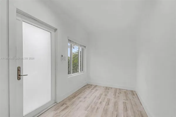 a view of an empty room with wooden floor and a window