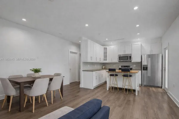 a kitchen with stainless steel appliances kitchen island granite countertop a table chairs and a stove top oven