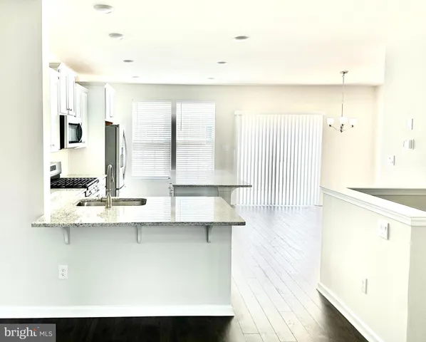 a view of a kitchen with kitchen island white cabinets and stainless steel appliances