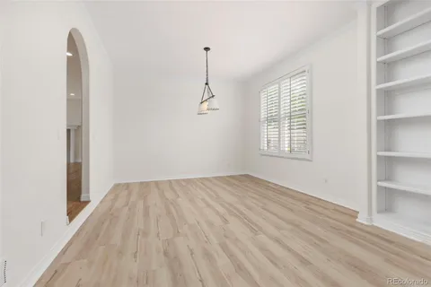 a view of empty room with wooden floor and fan