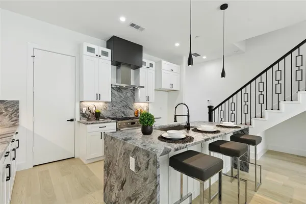 a kitchen with stainless steel appliances kitchen island granite countertop a table chairs and a refrigerator