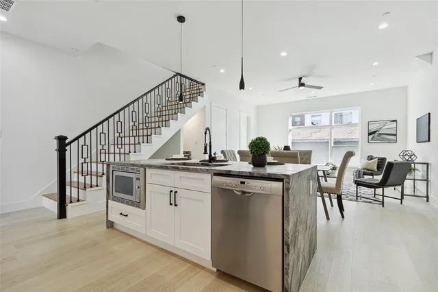 a open kitchen with stainless steel appliances granite countertop a stove a sink a dining table and chairs with wooden floor