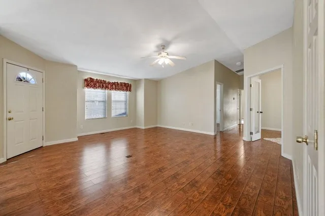 a view of an empty room with wooden floor and a window