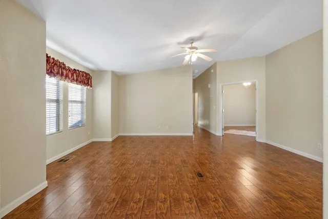 a view of an empty room with wooden floor and a window